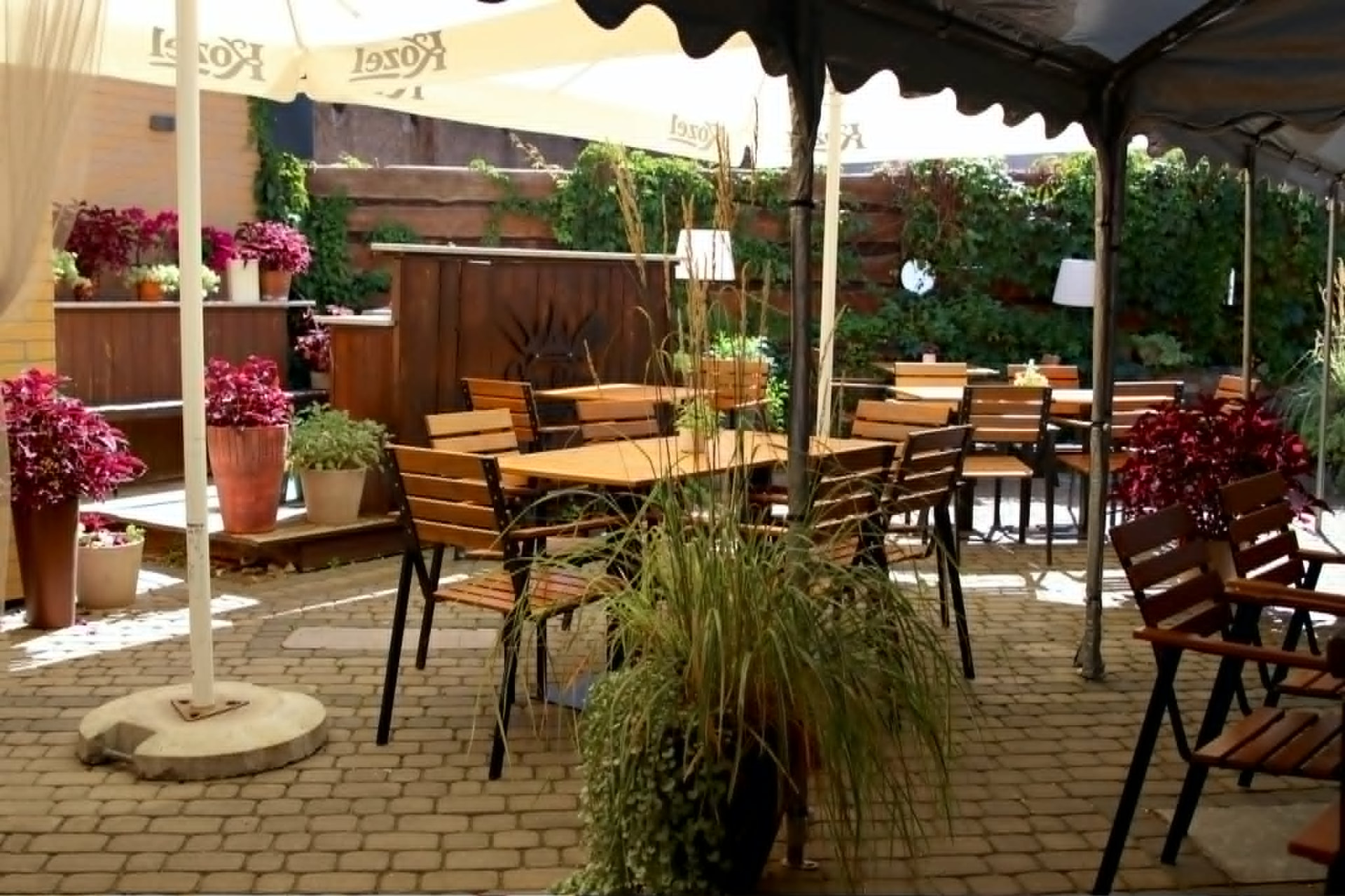 Ogródek restauracji Stare Bojary w Białymstoku — stoliki pod parasolami i kwiaty